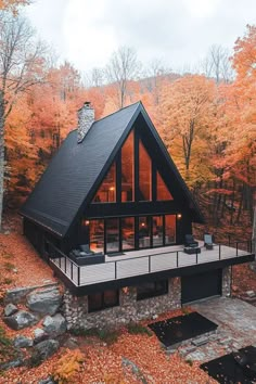 a house in the woods surrounded by fall foliage and trees with orange leaves on them