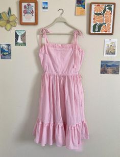 Breeze through sunny days in this charming pink cotton sundress! Lightweight and flowy, this dress is perfect for warm weather, offering effortless style and comfort. The playful tie shoulders and adjustable waist ties let you customize the fit, while the gathered neckline adds a sweet, feminine touch. And with inseam pockets, you can keep your essentials close without sacrificing style. Whether you're strolling through the park or lounging by the beach, this sundress is your go-to for easy, breezy, and beautiful summer vibes! Key Features: - 100% lightweight cotton - Adjustable shoulder ties - Adjustable gathered waistband ties - Inseam pockets Size - Bust 36" - Waist 36" (adjustable to smaller) - Skirt length 26" (natural waist to hem) Gathered Neckline, Cotton Sundress, By The Beach, Beautiful Summer, Pink Cotton, Dress Clothes For Women, Waist Tie, Skirt Length, The Park