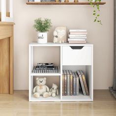 a white shelf with books, stuffed animals and pictures on it next to a fireplace