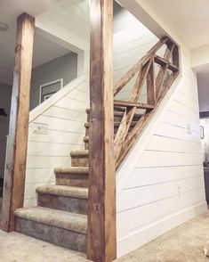 a dog is sitting on the floor in front of a stair case that has been made out of wood