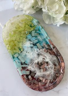 an oval shaped glass dish with mosaics and flowers in the background on a marble countertop