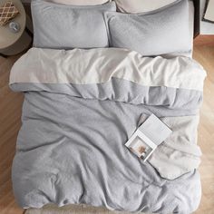 an overhead view of a bed with two pillows and a book on the pillowcase