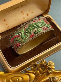 Antique Chinese Bangle. Andriani Vintage is pleased to offer for sale this lovely Vintage Bangle.  Green dragon breathing red fire on gold gilt looking alloy. Hand painted in enamel.  MEASUREMENTS  6cms inside diameter  2.2cms wide CONDITION In lovely condition some surface scratches and light signs of wear due to age  but nothing that detracts from the originality of this great piece. Item has original patina and has not be touched or cleaned.  Perfect gift for that special someone or indeed as Vintage Red Jewelry For Festivals, Traditional Red Jewelry For Collectible, Traditional Red Jewelry For Collectors, Red Vintage Jewelry For Festivals, Adjustable Red Bangle Cuff Bracelet, Red Bohemian Cuff Bracelet As Gift, Bohemian Red Cuff Bracelet As Gift, Bohemian Style Red Cuff Bracelet As Gift, Red Vintage Bracelets For Festivals