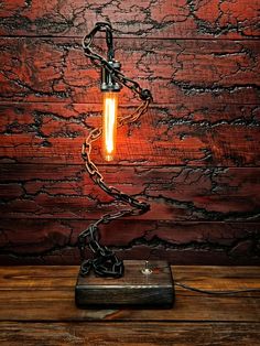 a light that is on top of a wooden table next to a chain hanging from the ceiling