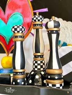 three chess pieces are sitting on a table next to a heart shaped wall hanging in the background