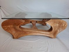 a wooden table with glass top sitting on a white sheeted surface in front of a white backdrop