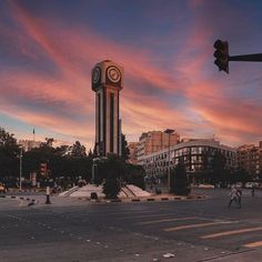 a tall clock tower sitting on the side of a road next to a traffic light