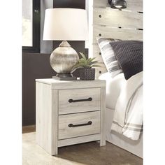 a night stand with two drawers and a lamp on top of the table next to it