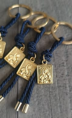 four gold and blue rope keychains on wooden table with metal rings attached to them