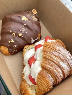 two pastries in a box with chocolate and strawberries