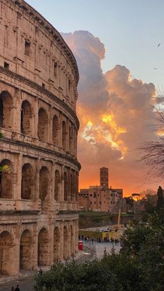 the roman colossion at sunset with clouds in the sky and people walking around