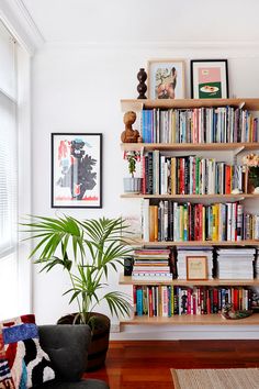 a living room filled with lots of books on top of a wooden shelf next to a window