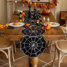 a dining room table decorated for halloween with spider web runner