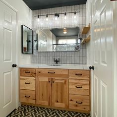 a bathroom with wooden cabinets and white tile on the walls, along with black and white patterned flooring