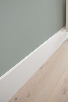 a white toilet sitting next to a green wall in a room with hardwood floors and walls