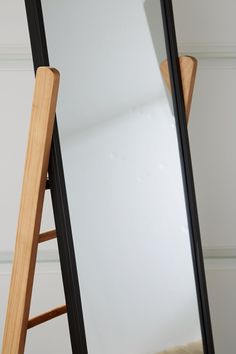 a wooden ladder leaning against a large mirror