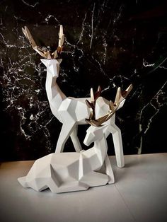 an origami deer sculpture sitting on top of a white table next to a black marble wall