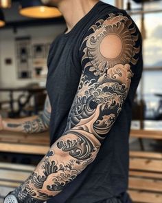 a man with a tattoo on his arm is standing in front of a counter top