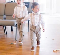 two young boys dressed in formal clothes walking through a room with chairs and trash on the floor