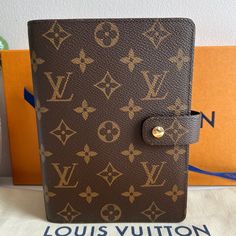 a brown and tan louis vuitton book with gold hardware on the front cover