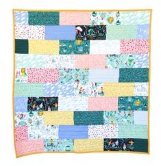 a colorful patchwork quilt hanging on the wall in front of a white background with an orange border