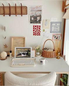 a laptop computer sitting on top of a white desk next to a basket and cup