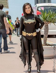 a woman dressed up as batgirl standing in the street with her hands on her hips