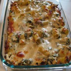 a casserole dish with cheese and spinach in it sitting on a table