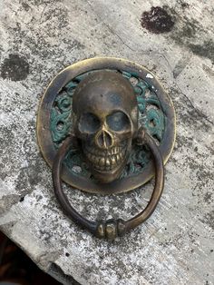 a skull door knocker on the side of a building with an ornate iron handle