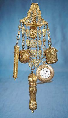 a gold clock with bells and chains hanging from it's side on a blue background