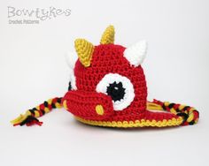 a crocheted red hat with yellow horns on it's brim is shown in front of a white background