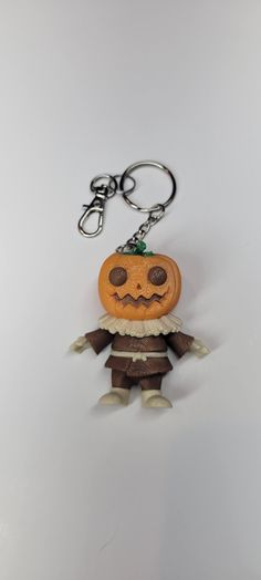 a pumpkin keychain with a creepy face on it's front and back