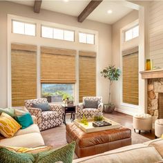 a living room with couches, chairs and a fire place in front of two windows