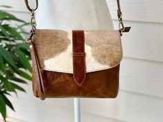 This gorgeous bag is crafted in Genuine Cowhide Hair on Skin and features natural cow print. The bag features real leather back and adjustable crossbody strap. Inside is cloth lined with lots of open and zip pockets. Size: 9.5 Inches x 7.5 Inches Light weight design; can be comfortably carried all day Durable real cowhide- low maintenance Easy to clean Leather Handbag Patterns, Cowhide Purse, Handmade Fabric Bags, Brown Cowhide, Leather Bag Pattern, Handbag Patterns, Leather Crossbody Purse, Gorgeous Bags, Purse Patterns