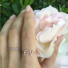 a woman's hand with a diamond ring on it and a flower in the background