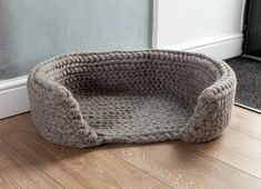 a gray dog bed sitting on top of a wooden floor