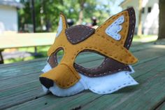 a close up of a stuffed animal mask on a wooden table with trees in the background