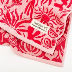 two towels with red and white designs are folded on top of each other in front of a white background