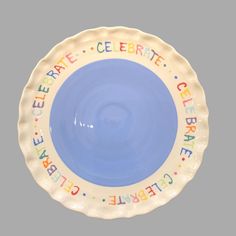 a blue and white plate with the words celebrate written in multicolored letters on it