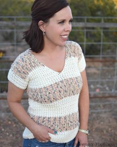 a woman standing in front of a fence with her hand on her hip and smiling