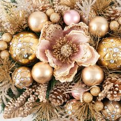 an arrangement of christmas ornaments and flowers in gold, pink and silver colors on a white background