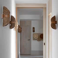 an open door leading to a hallway with baskets on the wall and hats hanging from hooks