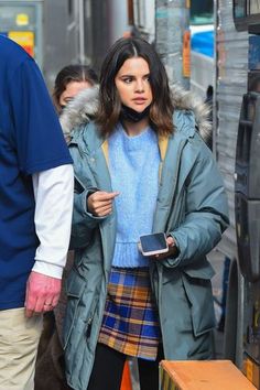 a woman is standing in front of a bus and looking at her cell phone as she walks down the street