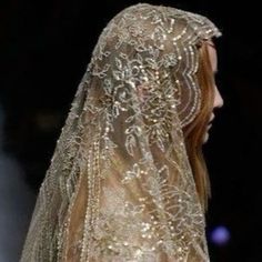 the back of a woman's head wearing a veil and dress with beading on it