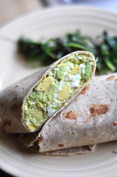 there is a burrito on the plate with spinach