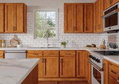 a kitchen with wooden cabinets and marble counter tops, along with white tile backsplash