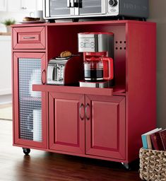 a microwave oven sitting on top of a red cabinet next to a toaster and coffee maker