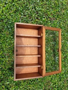 an open wooden box sitting on top of a lush green field next to a hedge