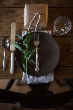 a place setting on a wooden table with silverware and napkins in the middle