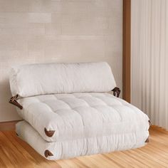 a white futon bed sitting on top of a hard wood floor next to a wall